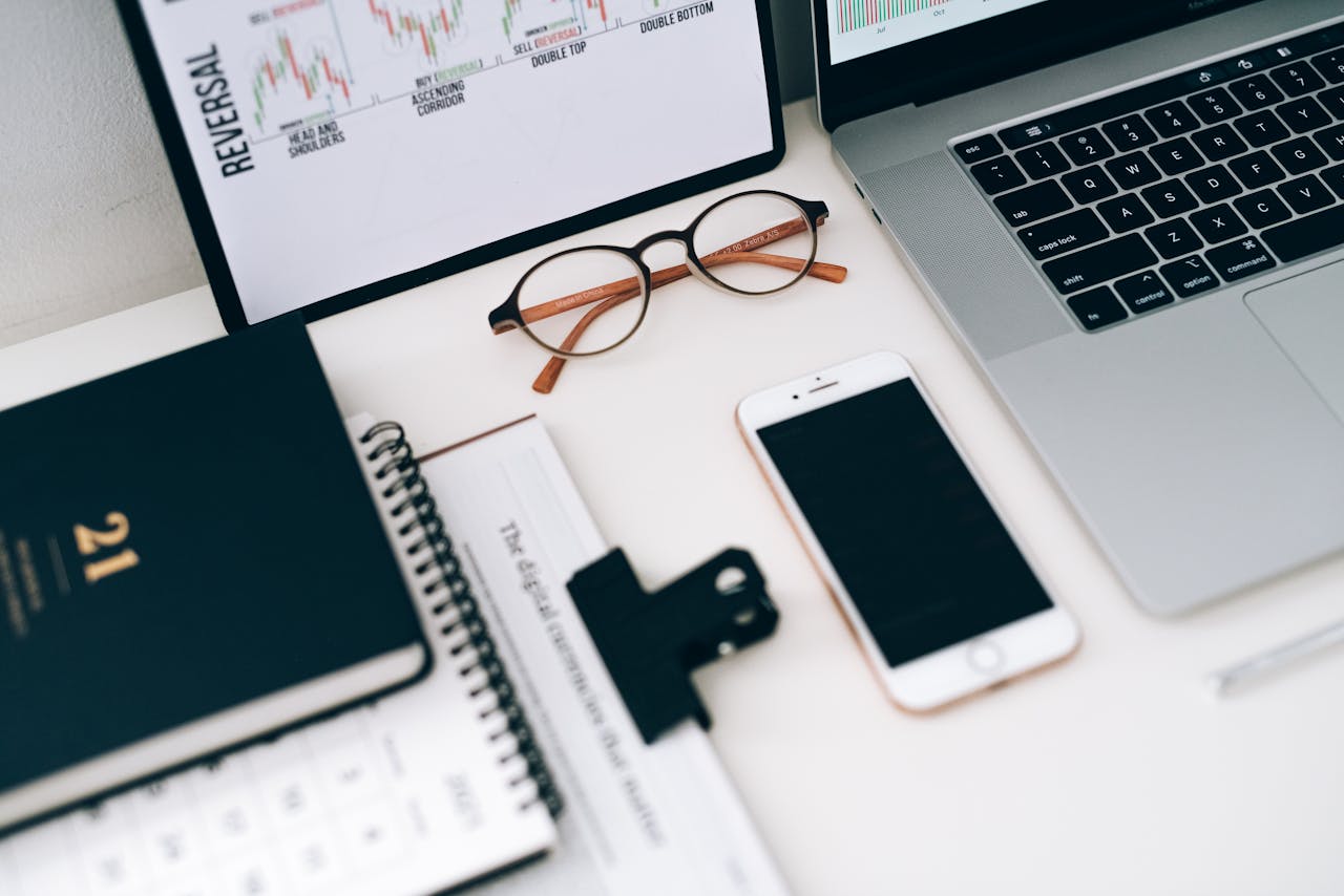 A modern work desk setup featuring electronic devices and financial graphs for productivity.